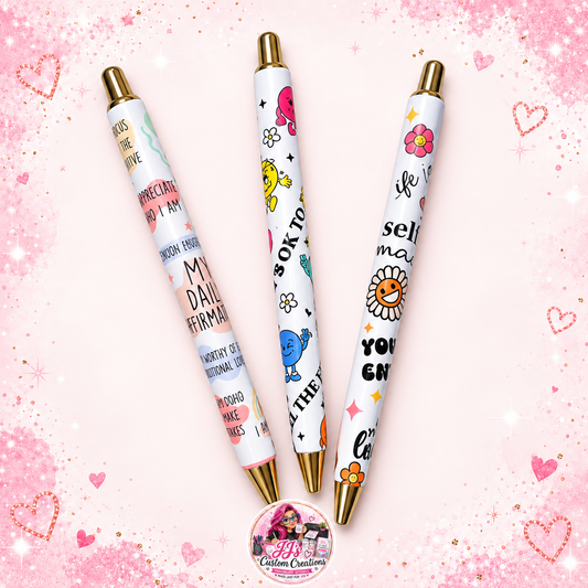 Three affirmation pens with gold details on a pale pink sparkle background with JJ's watermark