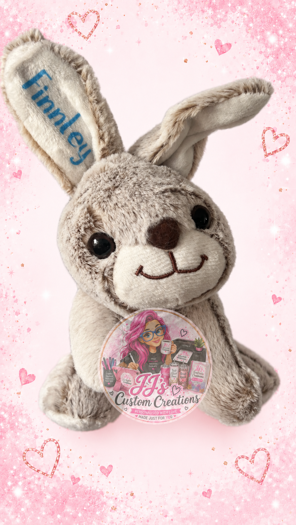 Close-up personalised grey Finnley bunny teddy on JJ's pink sparkle background