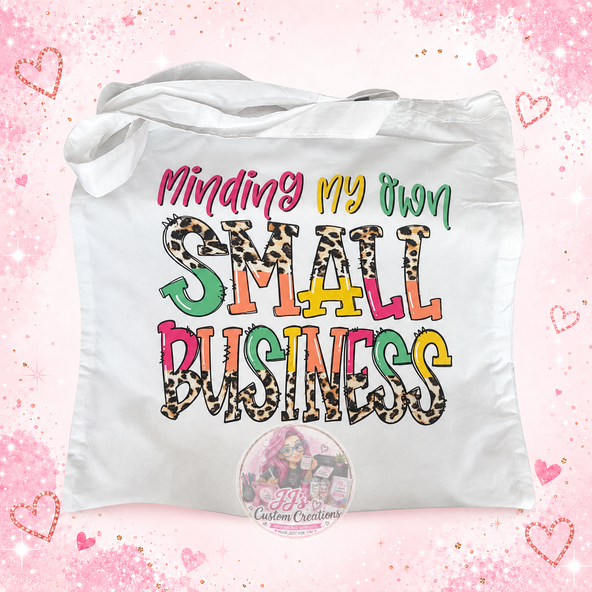 Minding My Own Small Business white tote bag on pale pink sparkle background with JJ's watermark