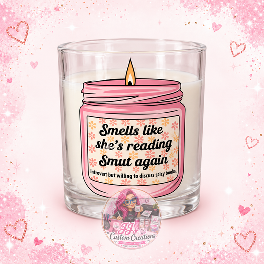 Smells Like She's Reading Smut Again scented candle on pale pink sparkle background with JJ's watermark